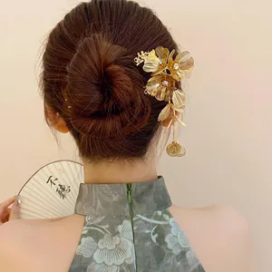 Detailed view of a gold floral hair stick with rhinestones and a dangling tassel