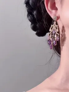 Gros plan d'élégantes boucles d'oreilles vintage en plaqué or 18K et zircons sur modèle.