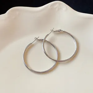Detail view of minimalist silver hoop earrings displayed on a cream decorative plate