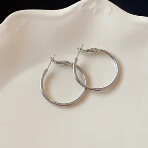 Close-up of minimalist silver round hoop earrings on a decorative ceramic plate