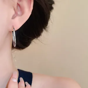 Close-up of silver-toned circular hoop earrings worn on a model's ear
