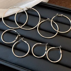 Set of multiple silver hoop earrings in different sizes on a black display tray