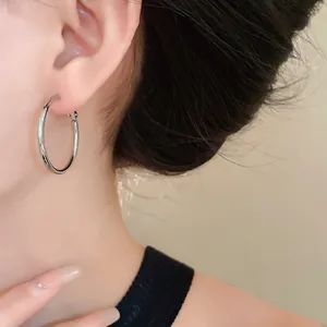 Close-up detail of minimalist silver-toned circular hoop earrings worn on the ear