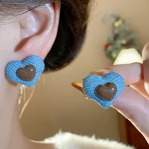 Detailansicht der blauen Denim-Herz-Ohrringe mit braunem Harzzentrum am Model