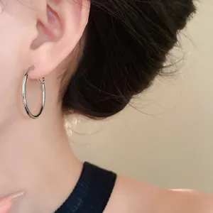 Macro view of minimalist silver hoop earring worn on the ear showing sleek finish