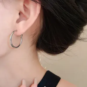 Macro detail view of a minimalist silver hoop earring worn on an Asian woman's ear