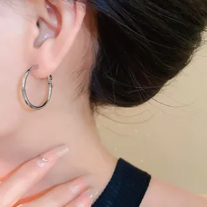 Detailed view of a model wearing a minimalist silver-colored large hoop earring.