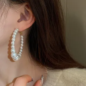 Close-up of large pearl hoop earrings worn by a model in a French vintage style.