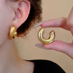 Chunky gold C-shaped hoop earrings with steel needles in minimalist vintage style