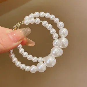 Detailed view of oversized hoop earrings featuring graduated white pearls in vintage style