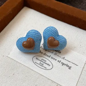 Detailansicht der Herz-Ohrstecker mit blauem Denim-Stoff und braunem Harz-Herzchen