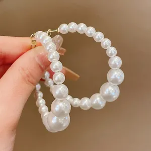 Close-up detail of vintage style graduated pearl hoop earrings with gold-tone closure