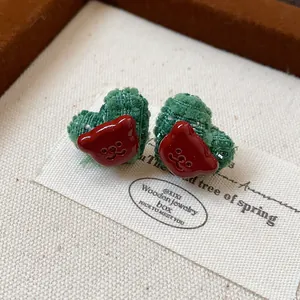 Detailansicht herzförmiger grüner Tweed-Ohrstecker mit roten Bärengesichtern aus Harz