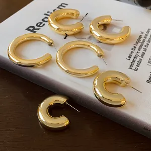 Chunky minimalist gold C-shaped hoop earrings displayed on an open white book page
