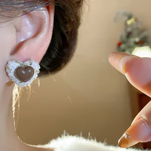 Detailaufnahme eines herzförmigen Harzohrrings mit elegantem weißem Tweed-Stoffbesatz