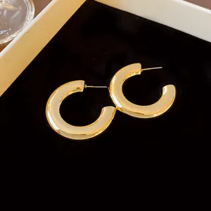 Close-up of chunky gold C-shaped hoop earrings with minimalist polished finish