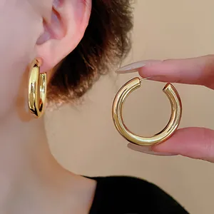 Detailed macro shot of minimalist gold C-shaped hoop earrings with a polished mirror finish