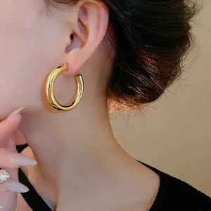 Macro view showing the polished gold finish of minimalist C-shaped hoop earrings on ear