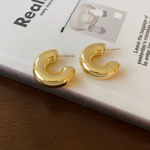 Detailed macro view of golden C-shaped hoop earrings with a polished mirror finish