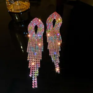 Close-up of elegant long tassel earrings with multi-colored rhinestones on a dark surface