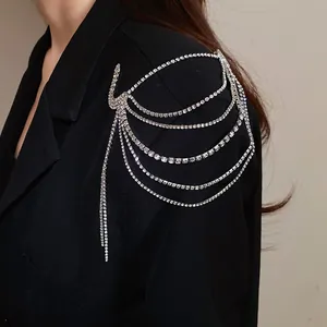 Detailed macro view showing a sparkling multi-layer rhinestone tassel brooch on a shoulder