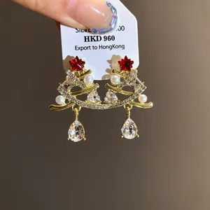 Primo piano di orecchini ad albero di Natale con stelle rosse, cristalli e perle bianche