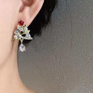 Primo piano di un orecchino a forma di albero di Natale con perle e strass sull'orecchio