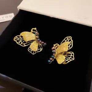 Detailansicht goldener Vintage-Schmetterlingsohrringe mit bunten Perlen in Box