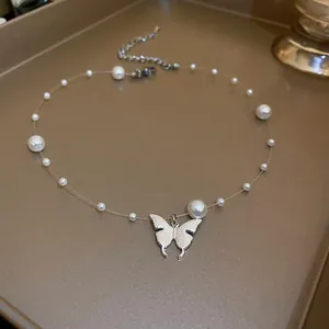 Close-up of silver butterfly pendant and pearls on a transparent necklace cord