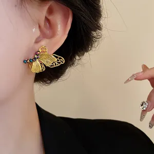 Detailansicht eines vintage goldfarbenen Schmetterlings-Ohrsteckers mit Strass am Ohr