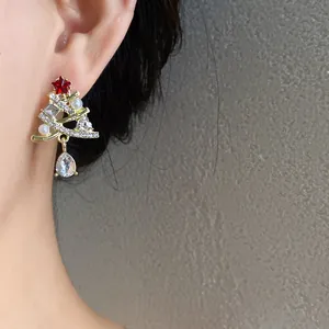Dettaglio di orecchini a lobo ad albero di Natale con perle e strass brillanti