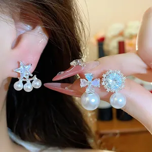 Close-up detail of elegant silver needle zircon star and flower earrings with pearl pendants