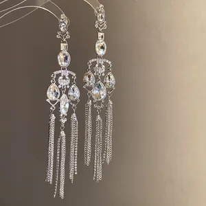 Macro view of luxurious silver earrings with teardrop crystals and long chain tassels
