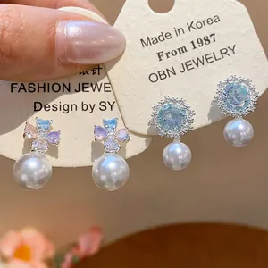 Detailed macro shot of zircon flower and pearl drop earrings on display card
