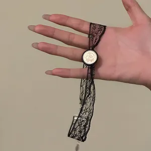 Detail view of a black lace choker with an engraved gold floral resin button.