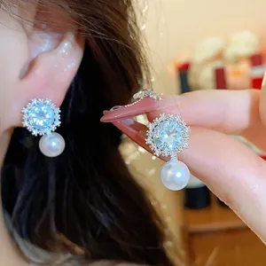 Close-up of elegant silver flower stud earrings with sparkling zircon and pearl drop
