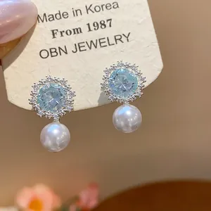 Detailed view of elegant zircon star flower earrings with lustrous white pearl drops.