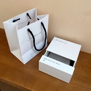 Elegant white jewelry box and matching gift bag set with minimalist typography