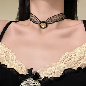 Detail shot of an elegant black lace choker with a delicate gold rose flower ornament.