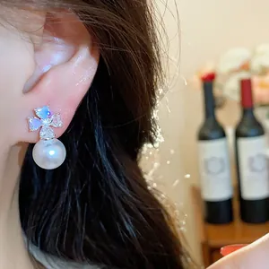 Detailed view of silver flower stud earrings with sparkling zircons and a white pearl