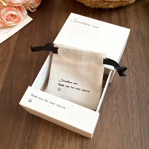Close-up of white textured gift box and linen drawstring bag for jewelry storage