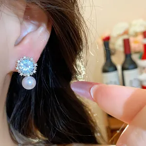 Detail shot of zircon star flower earrings with dangling pearl on a model's ear.