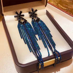 Detailed macro of long blue zircon tassel earrings with star studs in a luxury box
