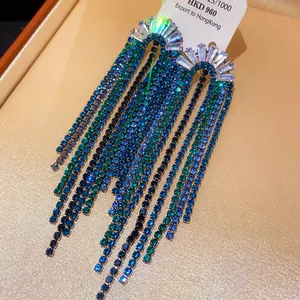 Close-up detail of elegant silver tassel earrings featuring blue and green zircon stones