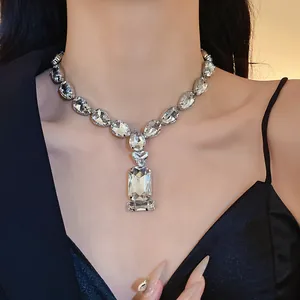Close-up detail of luxurious teardrop and square crystal pendant necklace for gala dresses.