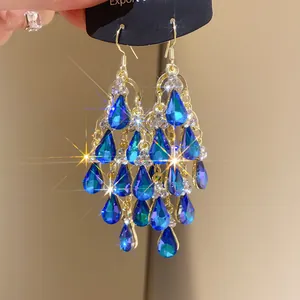 Exquisite close-up of vintage gold tassel earrings featuring vibrant blue teardrop zircons