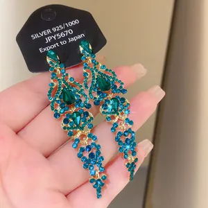 Detailed macro shot of vintage emerald green tassel earrings featuring brilliant zircon crystals.