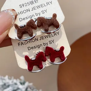 Detailed view of red and brown flocked rocking horse stud earrings with silver needles