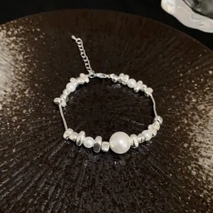 Detailed view of a titanium steel bracelet with irregular silver nuggets and pearls.