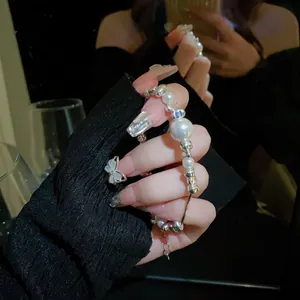 Close-up of titanium steel pearl and shattered silver bead bracelet worn on a hand.